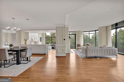 Living room with decorative columns, expansive windows, light wood-type flooring, and an inviting chandelier | Image 1