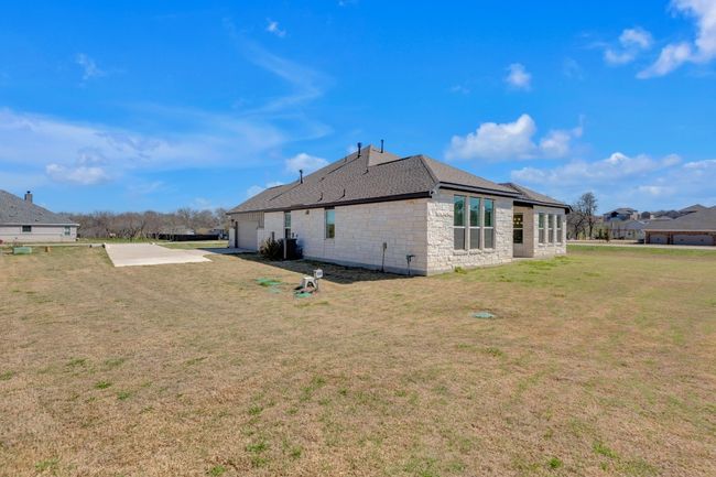 Back of house with stone siding, a lawn, and roof with shingles | Image 36