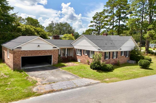Single story home featuring a chimney, asphalt driveway, a garage, and brick siding | Image 30