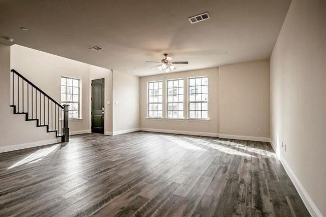 Unfurnished living room with stairs, dark wood-style floors, visible vents, and a ceiling fan | Image 5
