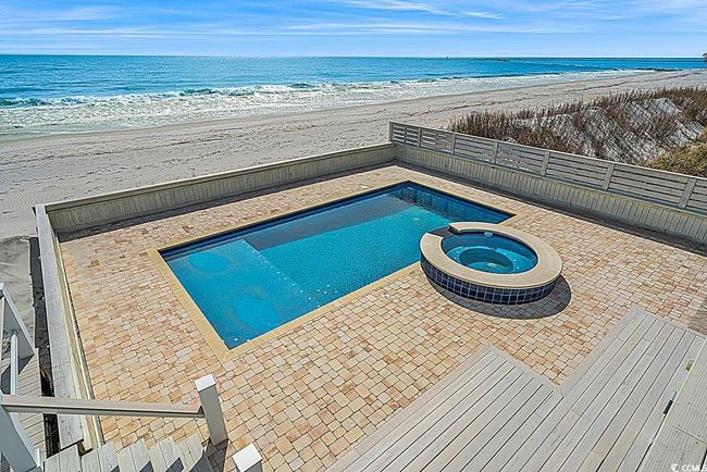 View of swimming pool with a pool with connected hot tub, a water view, a patio, and a beach view | Image 21