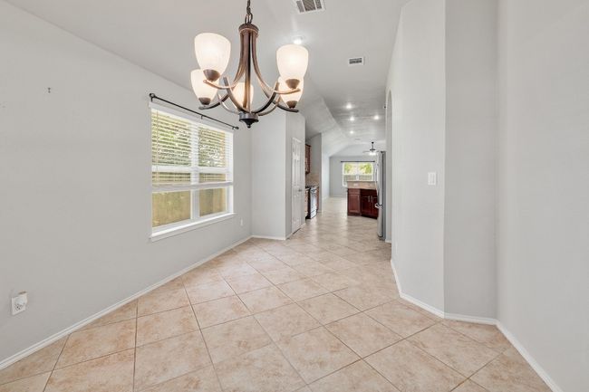 Unfurnished room featuring a chandelier, light tile patterned flooring, and lofted ceiling | Image 10