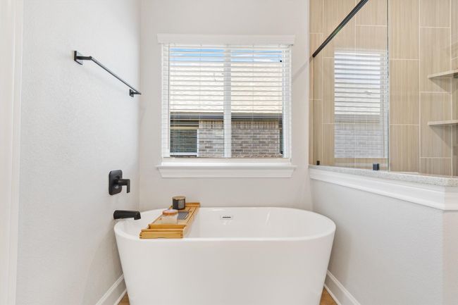 Full bathroom featuring a freestanding tub, a tile shower, and baseboards | Image 12