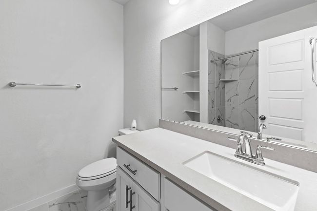 Bathroom with marble look tiles, baseboards, vanity, a shower, and toilet | Image 32