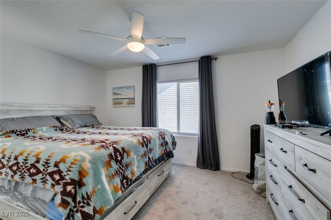 Bedroom featuring visible vents, baseboards, light colored carpet, and ceiling fan | Image 27