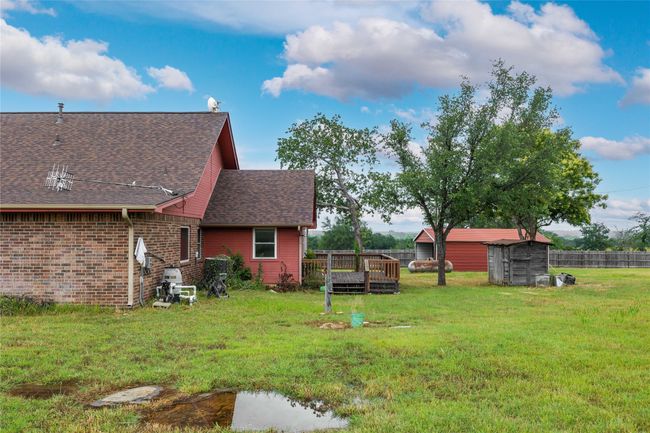View of yard featuring a storage unit and a wooden deck | Image 25