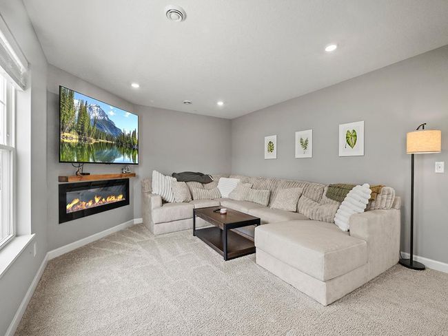 Completing the main level is a cozy living room retreat. Remote-controlled electric fireplace, and plush carpeting. | Image 10