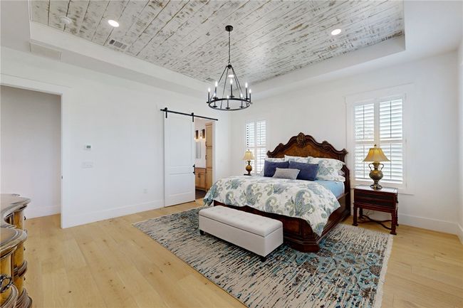 Bedroom featuring a tray ceiling, a barn door, wooden ceiling, baseboards, and a chandelier | Image 17