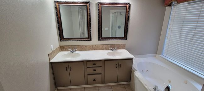 Bathroom with double vanity, a jetted tub, a textured wall, and tile patterned flooring | Image 12