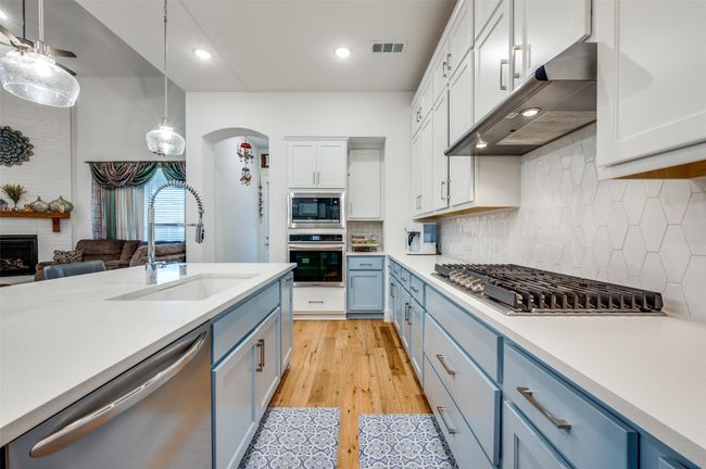 Kitchen featuring appliances with stainless steel finishes, blue cabinetry, light countertops, range hood, and recessed lighting | Image 11