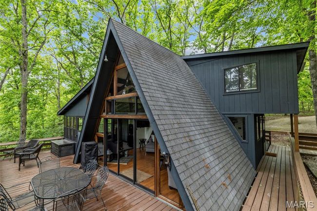 Rear view of property with a wooden deck, outdoor dining area, roof with shingles, and a sunroom | Image 59
