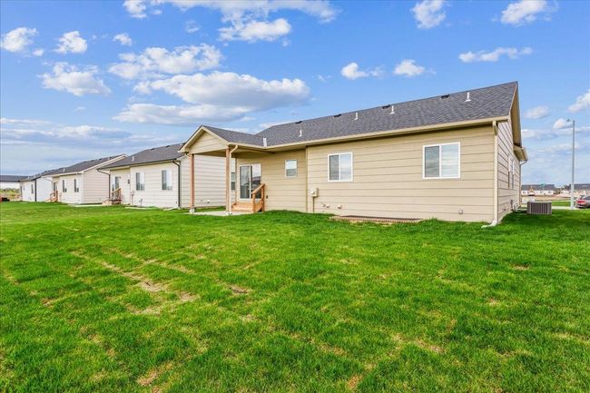 Back of house featuring a yard, entry steps, central AC, and a shingled roof | Image 28