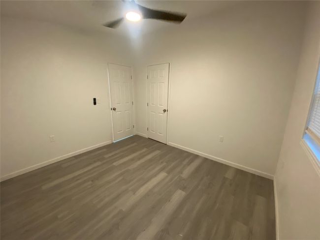 Empty room with a ceiling fan, dark wood finished floors, and baseboards | Image 14