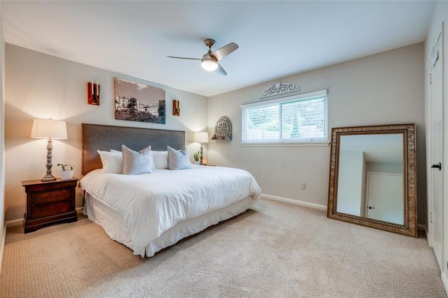 Spacious Primary bedroom features neutral-toned walls, carpeted flooring, ceiling fan, large closet & en suite bathroom | Image 20