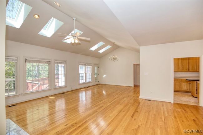 Unfurnished living room with a skylight, visible vents, an inviting chandelier, and light wood-type flooring | Image 8