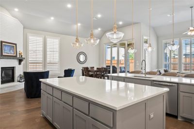 Kitchen with a center island, dark hardwood / wood-style floors, gray cabinetry, a brick fireplace, and stainless steel dishwasher | Image 3