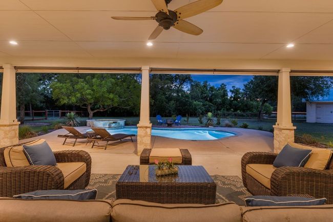 The expansive back patio provides the perfect space for outdoor dining and relaxation, overlooking the pool and lush greenery. | Image 29
