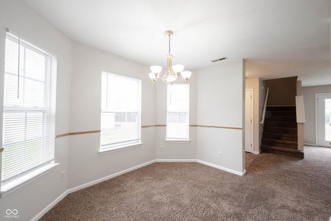 spare room featuring an inviting chandelier, visible vents, carpet, and plenty of natural light | Image 12