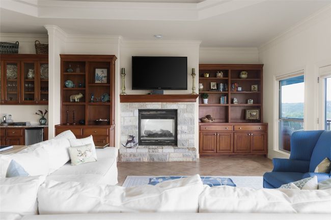 Living area featuring ornamental molding, a stone fireplace, and light tile patterned floors | Image 24