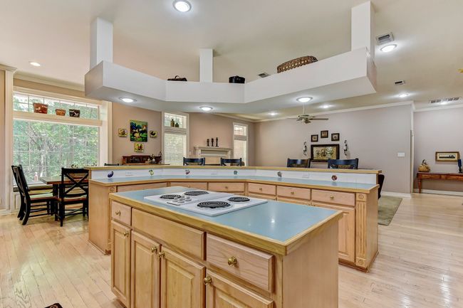 Kitchen featuring a center island, light wood-type flooring, ceiling fan, white electric cooktop, and visible vents | Image 13