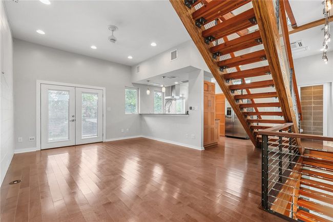 Unfurnished living room with stairway, wood finished floors, french doors, and recessed lighting | Image 8