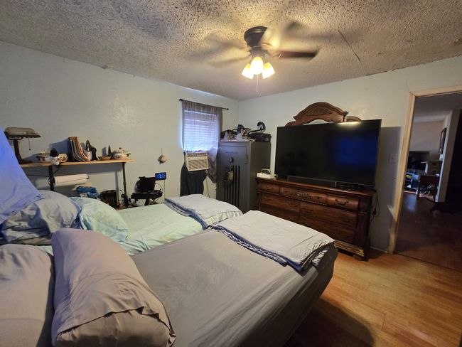 Bedroom featuring light wood-type flooring, a textured ceiling, and a ceiling fan | Image 20