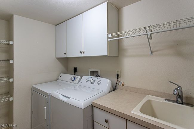Laundry area featuring cabinet space, washing machine and dryer, and a textured ceiling | Image 14