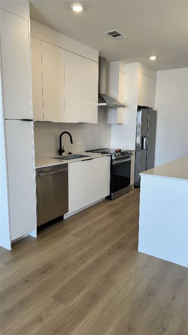 Kitchen featuring a sink, soft closing cabinets, appliances with stainless steel finishes, and wall chimney exhaust hood | Image 6