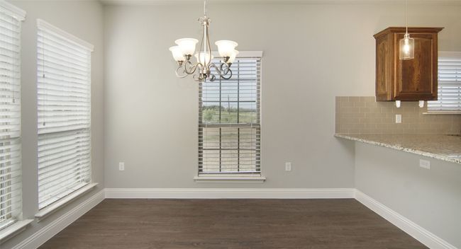 Unfurnished dining area featuring a chandelier, dark wood finished floors, and healthy amount of natural light | Image 4