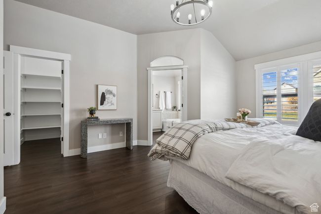 Bedroom featuring a spacious closet, a closet, dark hardwood / wood-style floors, ensuite bath, and a chandelier | Image 16