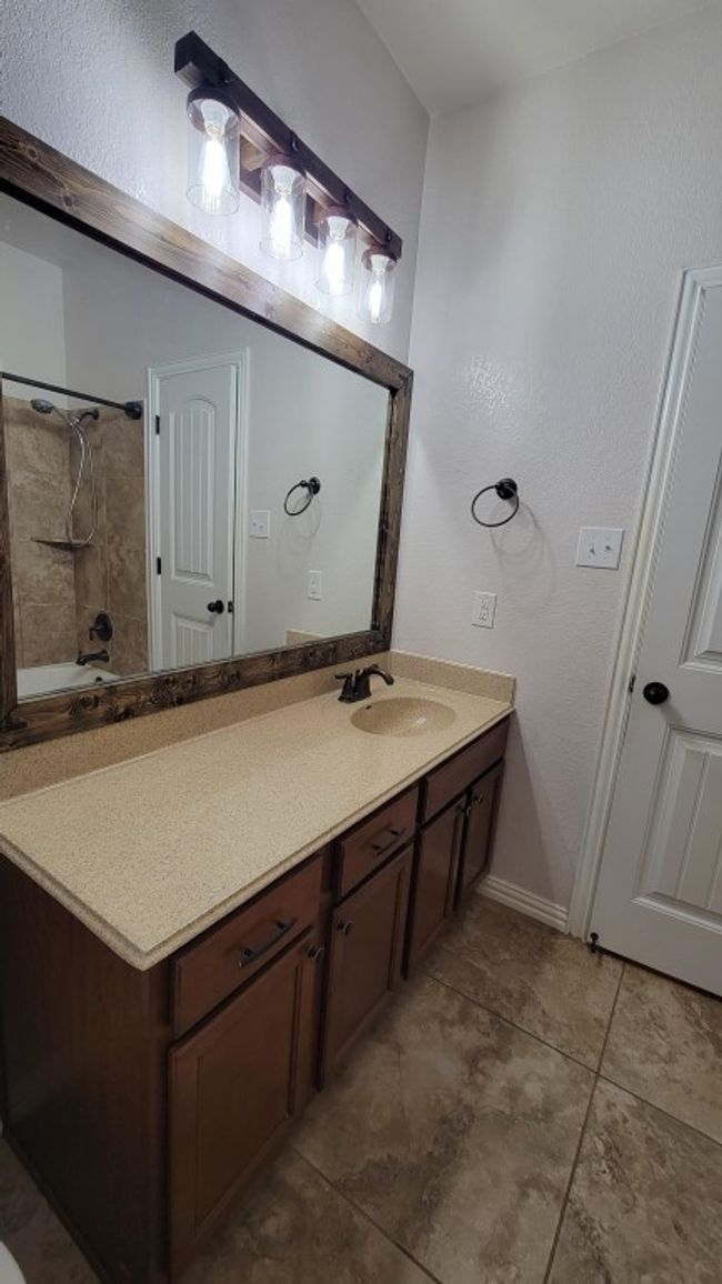 Full bath featuring vanity, tile patterned flooring, shower / tub combination, and baseboards | Image 11