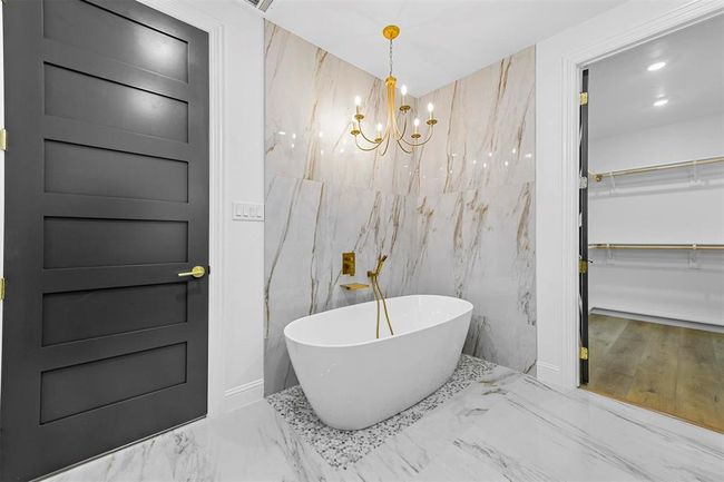 Bathroom featuring tile walls, a bathtub, tile floors, and an inviting chandelier | Image 28