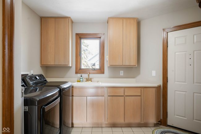 washroom featuring cabinet space, washing machine and dryer, and a sink | Image 32