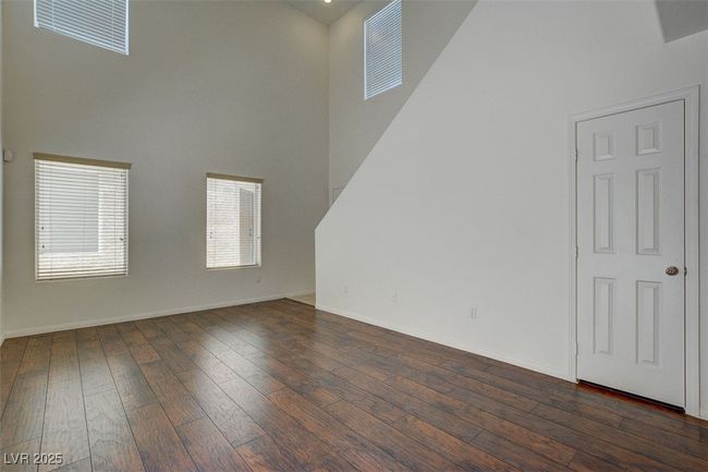 Unfurnished living room with a towering ceiling, visible vents, dark wood finished floors, and baseboards | Image 7