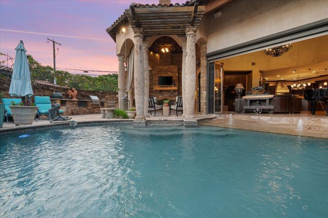 Pool at dusk with a patio area and an outdoor fireplace | Image 4