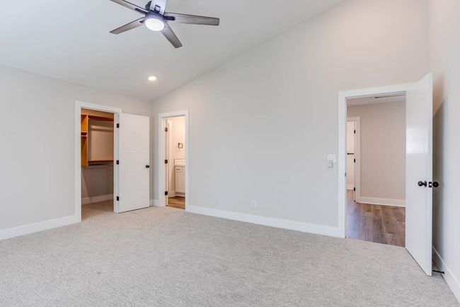 Unfurnished bedroom with vaulted ceiling, carpet floors, a walk in closet, recessed lighting, and baseboards | Image 20