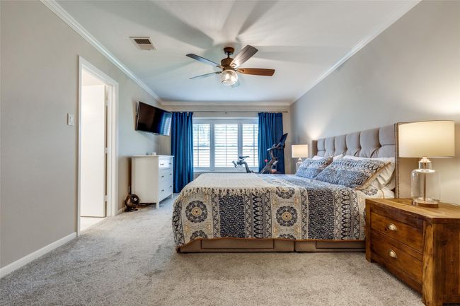 View of very nice-sized primary bedroom with shutters and drapes. | Image 14