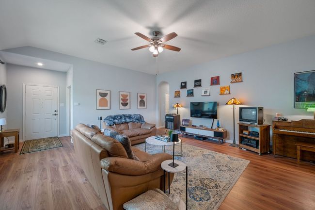 Living room featuring arched walkways, wood finished floors, ceiling fan, and baseboards | Image 6