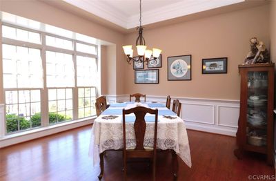 Dining room with ornamental molding, dark wood flooring, a notable chandelier, and a tray ceiling | Image 3