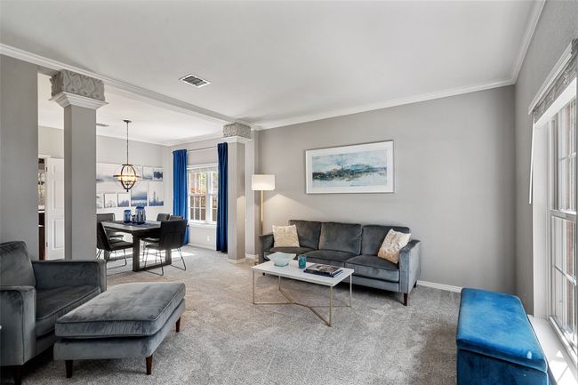 Carpeted living area with ornate columns, ornamental molding, baseboards, visible vents, and a notable chandelier | Image 4