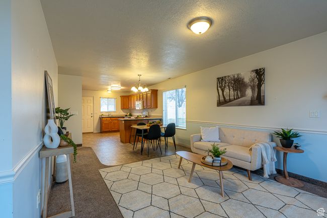 Living area with baseboards, a notable chandelier, and a textured ceiling | Image 6