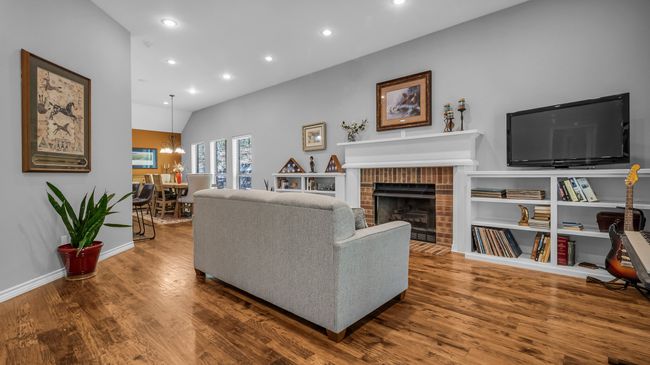 Living room with recessed lighting, a notable chandelier, wood finished floors, and a fireplace | Image 10
