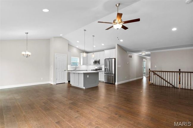 Unfurnished living room with a chandelier, a ceiling fan, baseboards, recessed lighting, and dark wood finished floors | Image 12