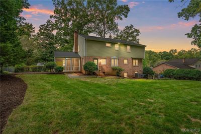 Back house at dusk featuring a lawn | Image 2