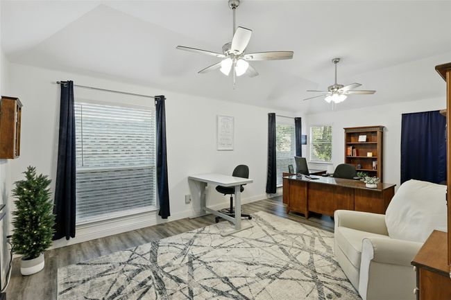 Large upstairs secondary bedroom featuring wood-like finished floors, ceiling fan, and lofted ceiling. Currently being used as an office. | Image 24