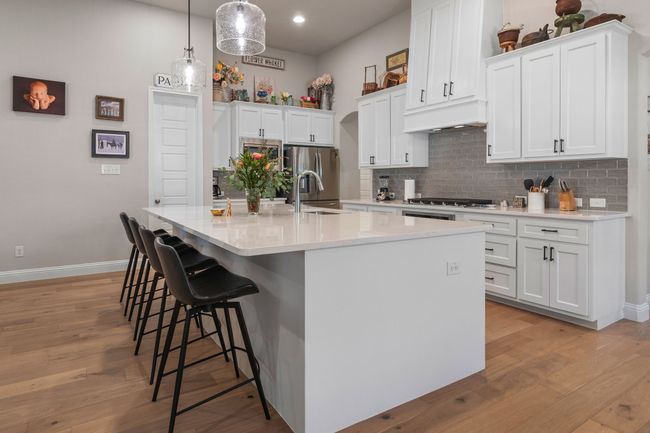 Kitchen featuring a kitchen bar, light wood-style floors, tasteful backsplash, and a sink | Image 6