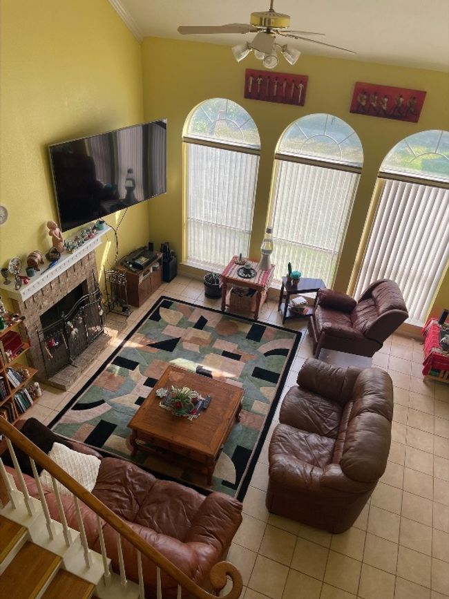 Living area with tile patterned floors, a ceiling fan, and a stone fireplace | Image 4
