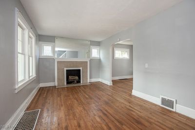 Unfurnished living room featuring a tiled fireplace and wood-type flooring | Image 2