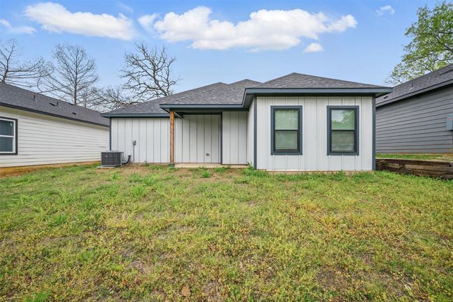 Back of house featuring roof with shingles, board and batten siding, central AC unit, and a lawn | Image 4