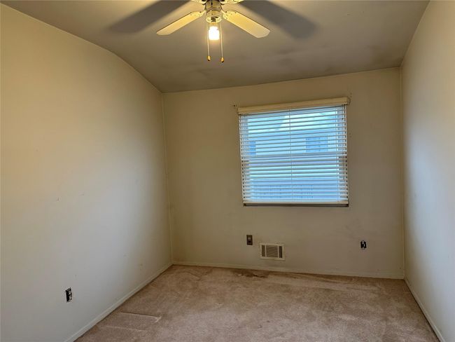 Empty room with light carpet, visible vents, baseboards, vaulted ceiling, and a ceiling fan | Image 6